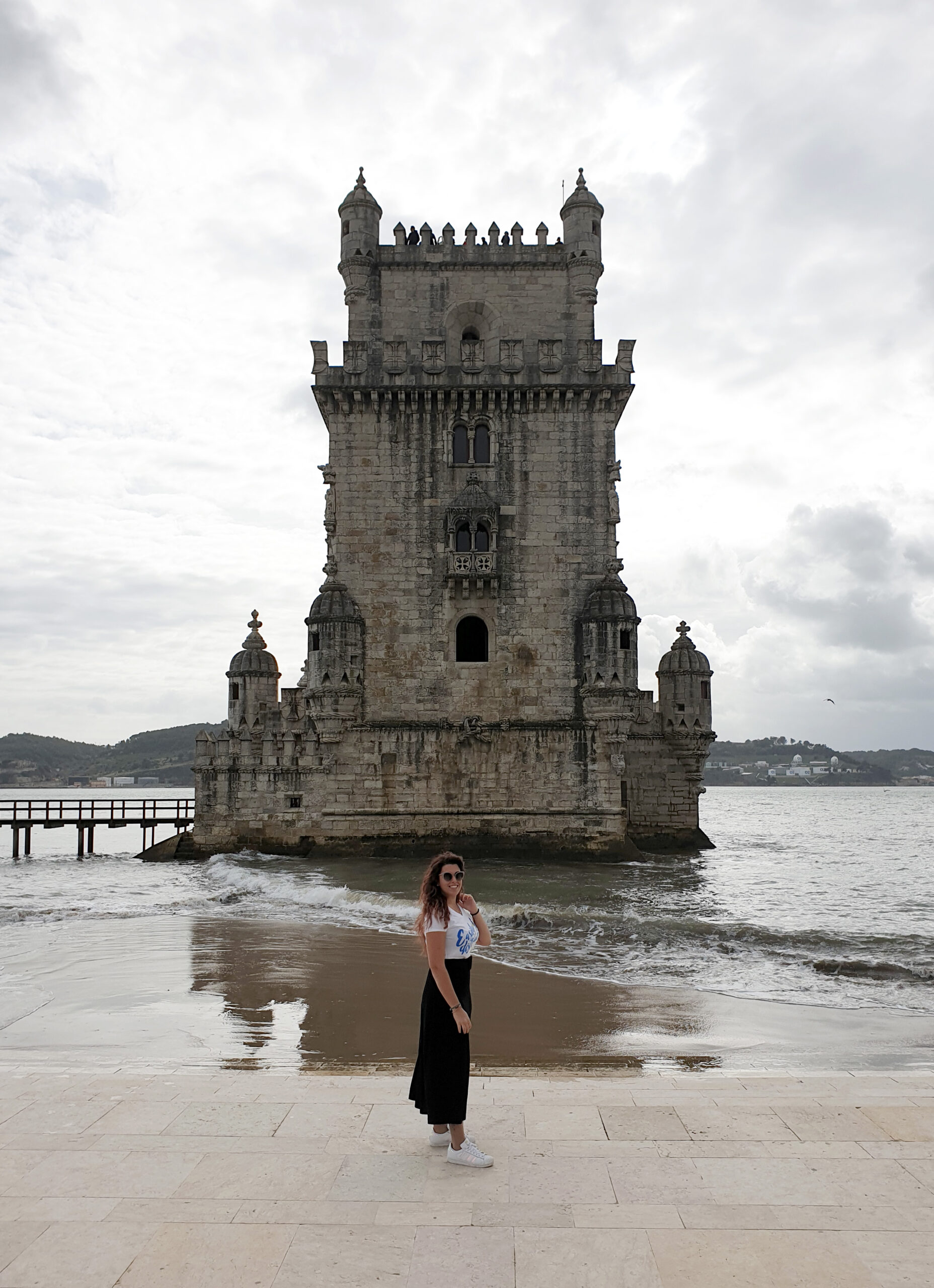 Carlotta sorridente in piedi di fronte alla torre di Belem, una antica torre fortificata, tappa obbligatoria quando si visita Lisbona in tre giorni