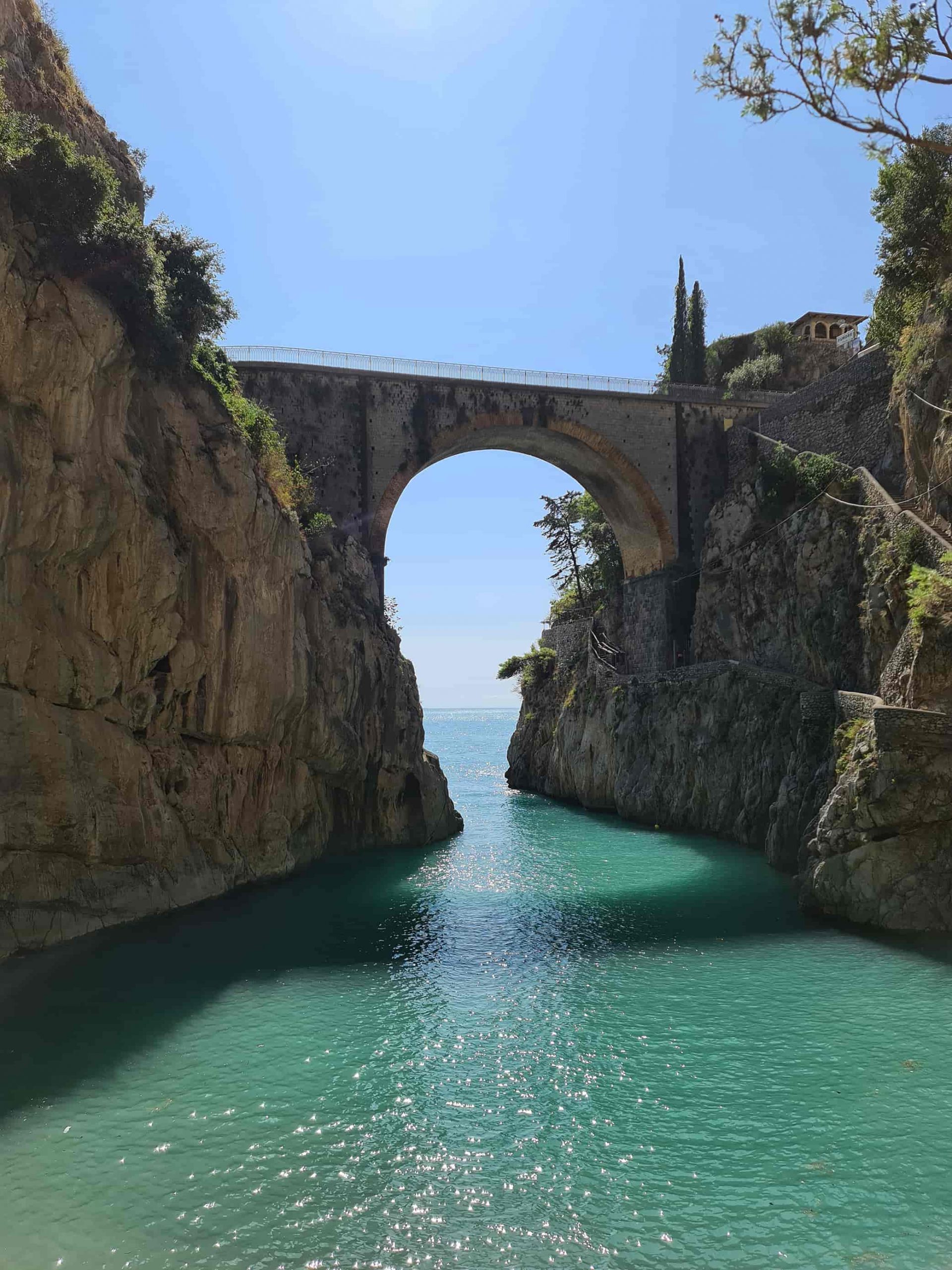 In foto si vede il Fiordo di Furore, una gola rocciosa con un ponte ad arco sospeso sul mare