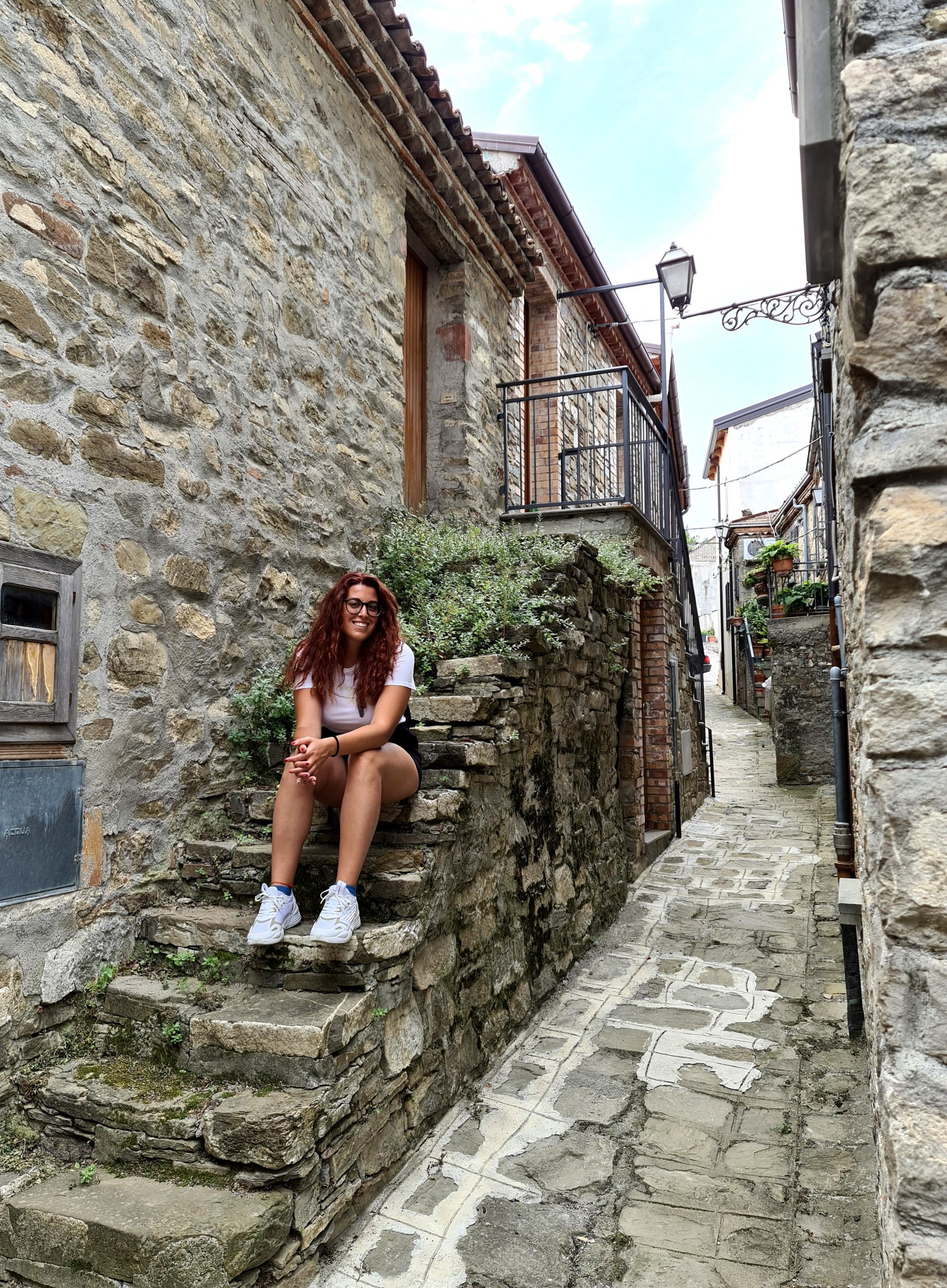 Carlotta seduta su una piccola scala in pietra nel borgo di San Paolo Albanese in Basilicata